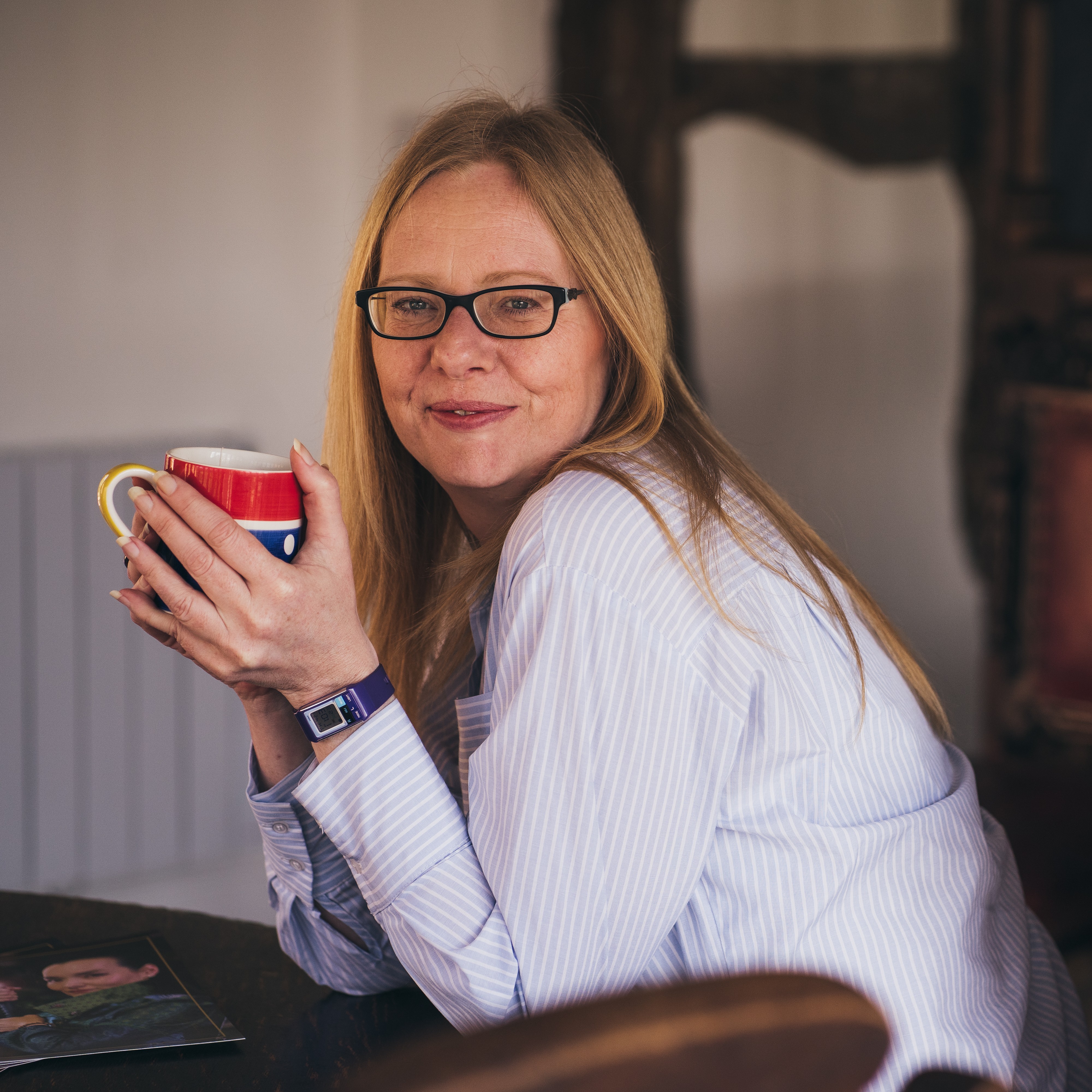 Kat sitting at a dining table, drinking a cup of tea